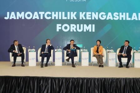 Panelists seated on a stage with microphones, under a blue banner reading FORUM.