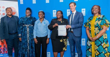 Photo of a group on a stage in front of a blue backdrop; one person holds a certificate.