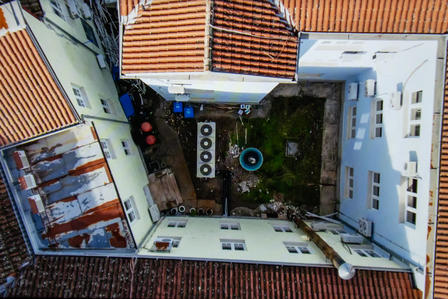 Aerial view of a white-walled courtyard with red-tiled roofs and a circular fountain.