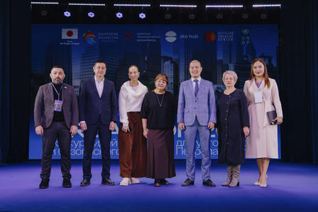 Eight people pose on a blue-lit stage at a formal event.