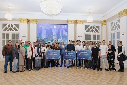 Group of people posing in a gold-trimmed ballroom; several hold blue banners.