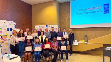 Group of diverse attendees in a conference room posing with certificates.