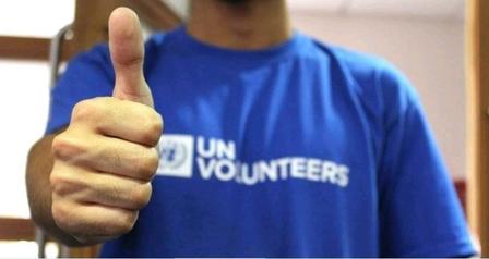 Photograph of a person in a blue UN Volunteers shirt giving a thumbs up.