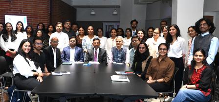 Photo: diverse group of professionals posing around a long conference table in a modern office.