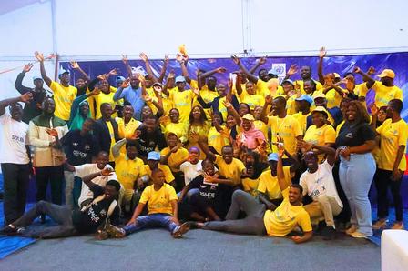 Large group of people in yellow shirts posing for a group photo in a gym.