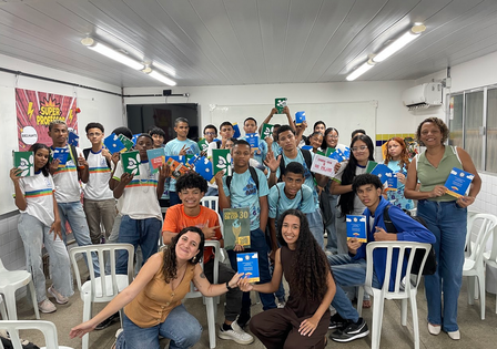 Group photo of smiling people in a bright room, holding blue certificates.