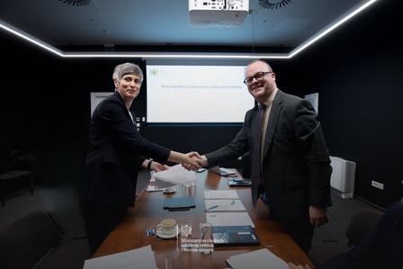Photograph of two businessmen shaking hands across a table in a modern conference room.