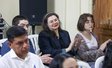Several people seated in a classroom or conference room, looking ahead.