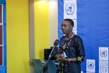 Person at a microphone in a bright room with a UNDP banners in the background.