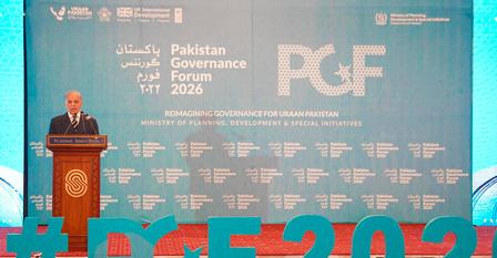 Photograph: man at podium delivering a speech on a conference stage with a blue backdrop and PGF logo.