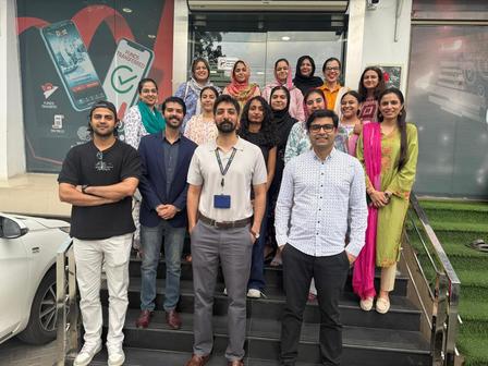 Group photo of diverse coworkers posing on outdoor stairs in front of an office building.