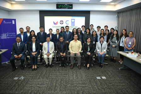 Group photo of professionals in a conference room with a banner backdrop.