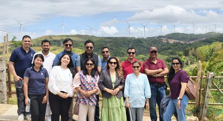Group of people posing on a terrace with hills and blue sky in the background.