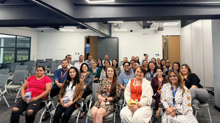 Diverse group posing for a photo in a conference room, with seated and standing attendees.