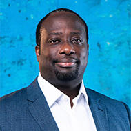 Portrait of a man in a blue suit with a white shirt; blue textured background.