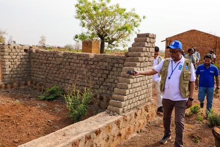 Photograph of UNDP Resident Representative in South Sudan inspecting a partially built brick wall at a resettlement camp.
