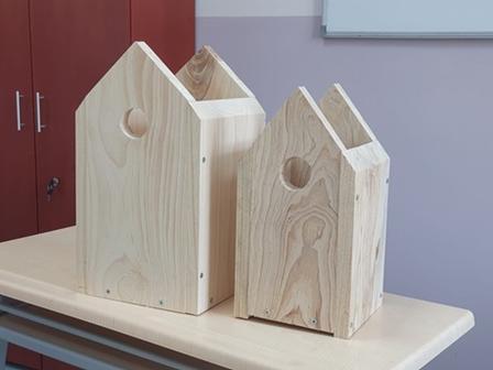 Three wooden house-shaped blocks on a light table in a room with red cabinets.