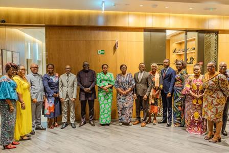 Group of people in colorful outfits posing in a wood-paneled hall.
