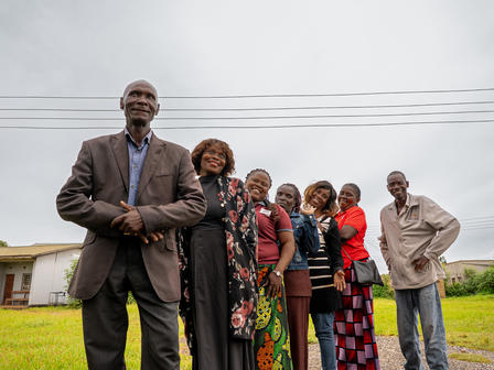 Photograph of a diverse group posing outdoors in front of a house.