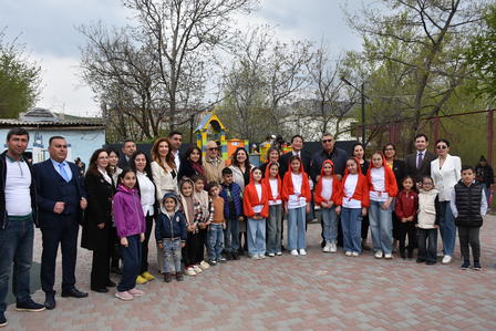 Group of adults and children wearing orange vests posing outdoors in a park.