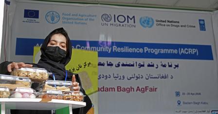 Photograph of a person at a stall with pastries, in front of an ACRP banner.