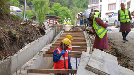 Construction site with workers in safety vests and hard hats building concrete steps.
