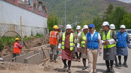 Line of construction workers in hard hats and reflective vests at a tunnel site.