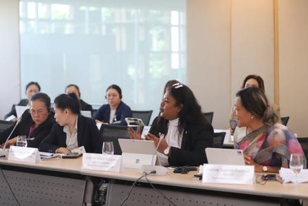 Photograph: Group of professionals seated at a conference table with laptops and nameplates.