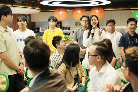 Group of people in a bright room, chatting and standing around tables at a social event.