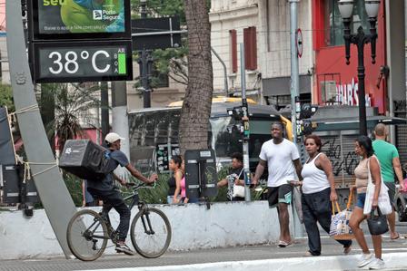 City street scene with cyclist and pedestrians; digital sign shows 38°C.