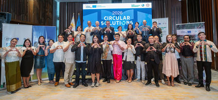 Group of people in formal attire posing on a stage in front of blue banners.