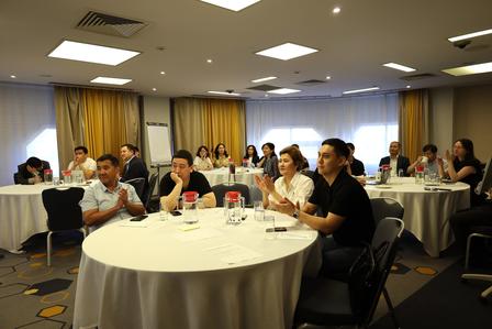 Photograph of conference attendees seated around round tables in a hotel meeting room.