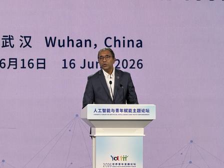 Male presenter at a podium on stage with a purple backdrop reading Wuhan, China.
