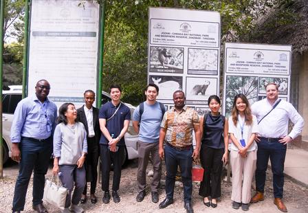 Group of people posing outdoors in front of large information display panels.