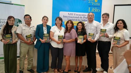 Group of people posing with certificates at a conference, banners in background.