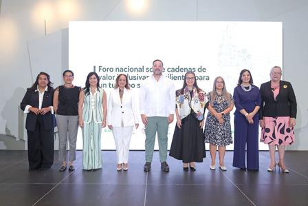 Group photograph of diverse people on stage at a conference in front of a bright screen.