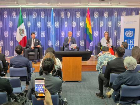 Panel discussion at a UN event with Iran and Afghanistan flags, audience seated.