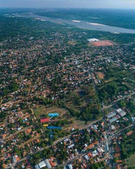 Aerial view of a coastal town with dense housing, roads, and green spaces along the water.