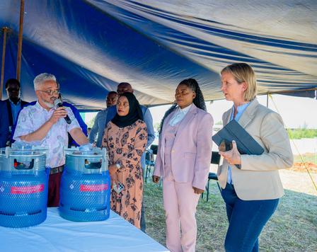 Photograph of a group of people at an outdoor event under a blue tent with two propane tanks.