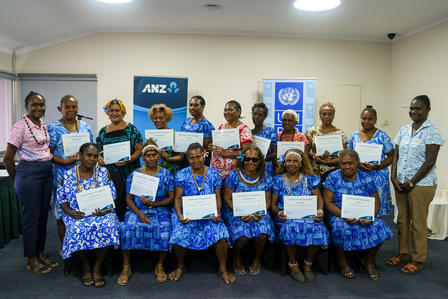 Group of children and adults posing with certificates at a UNICEF event in a conference room.