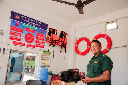 Photo: man in a green uniform standing in a room with red lifebuoys and posters.