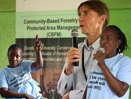 Photo: Two speakers at a forestry event, man in blazer and woman in blue shirt, microphones.