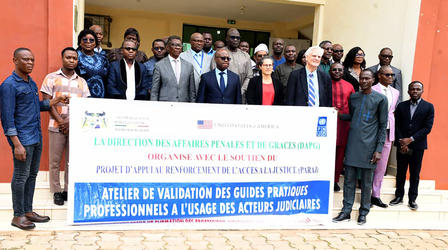 Group of diverse people posing with a banner about a professional workshop outside a building.