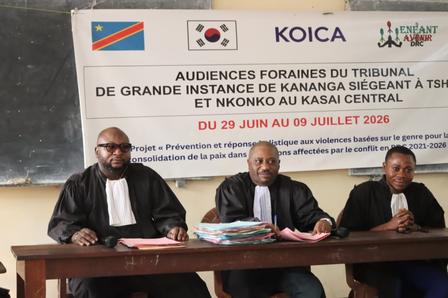 Three men in suits sign documents at a conference table, with a KOICA banner behind them.