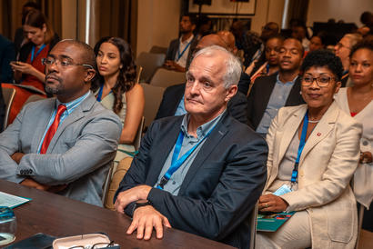 Attentive professionals in suits with blue lanyards seated at a conference table.