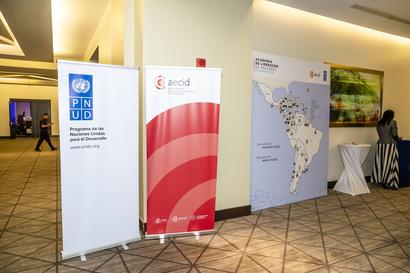 Indoor hallway with three vertical banners showing logos and a world map; a person in the background.