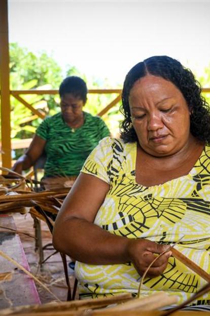 indigenous woman weaving a straw basket