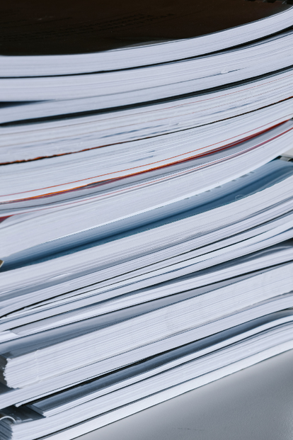 Stack of spiral-bound notebooks on a desk near a window.