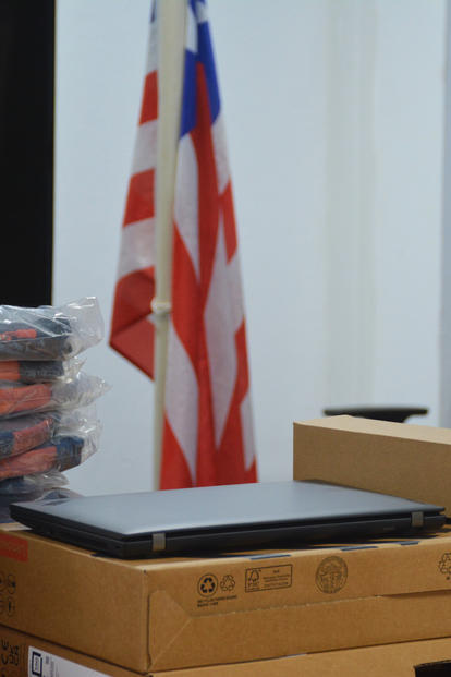 Office scene with stacked plastic-wrapped packages, cardboard boxes, and an American flag.