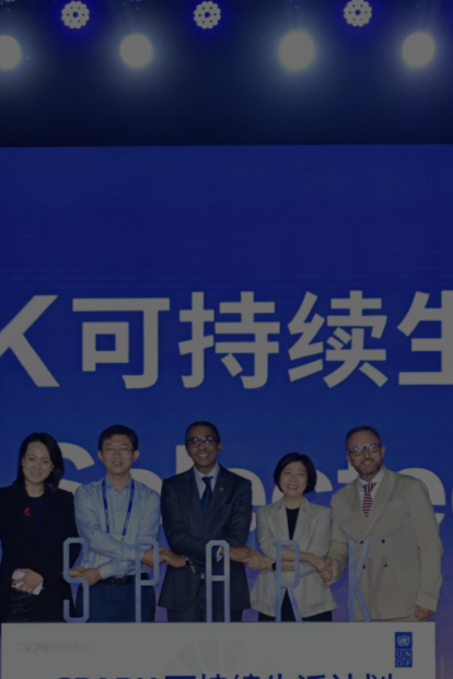Group of people on a stage under a blue SPARK 可持续生活计划 banner with stage lights.